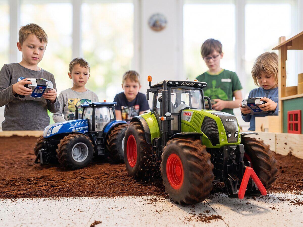 Kinder steuern ferngesteuerte Traktoren auf der Spielfläche